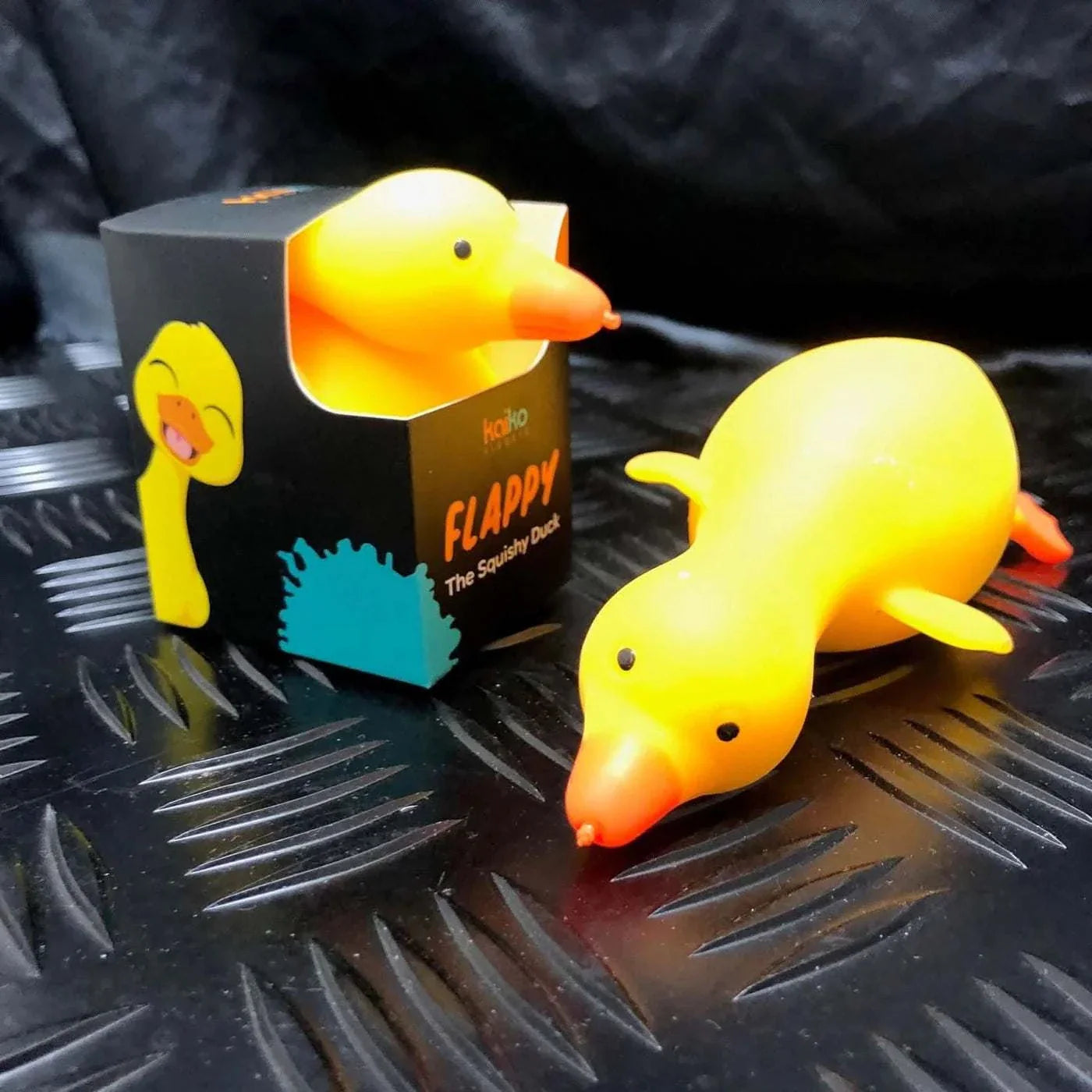 Flappy the Squishy Duck soft yellow foam toy with flapping neck, wings, and legs next to its black packaging box.
