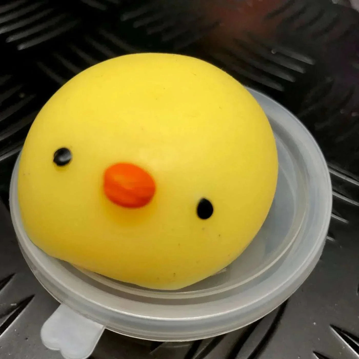 Yellow Jelly Mochi Squishy Animal shaped like a chick with an orange beak and black eyes on a clear plastic lid