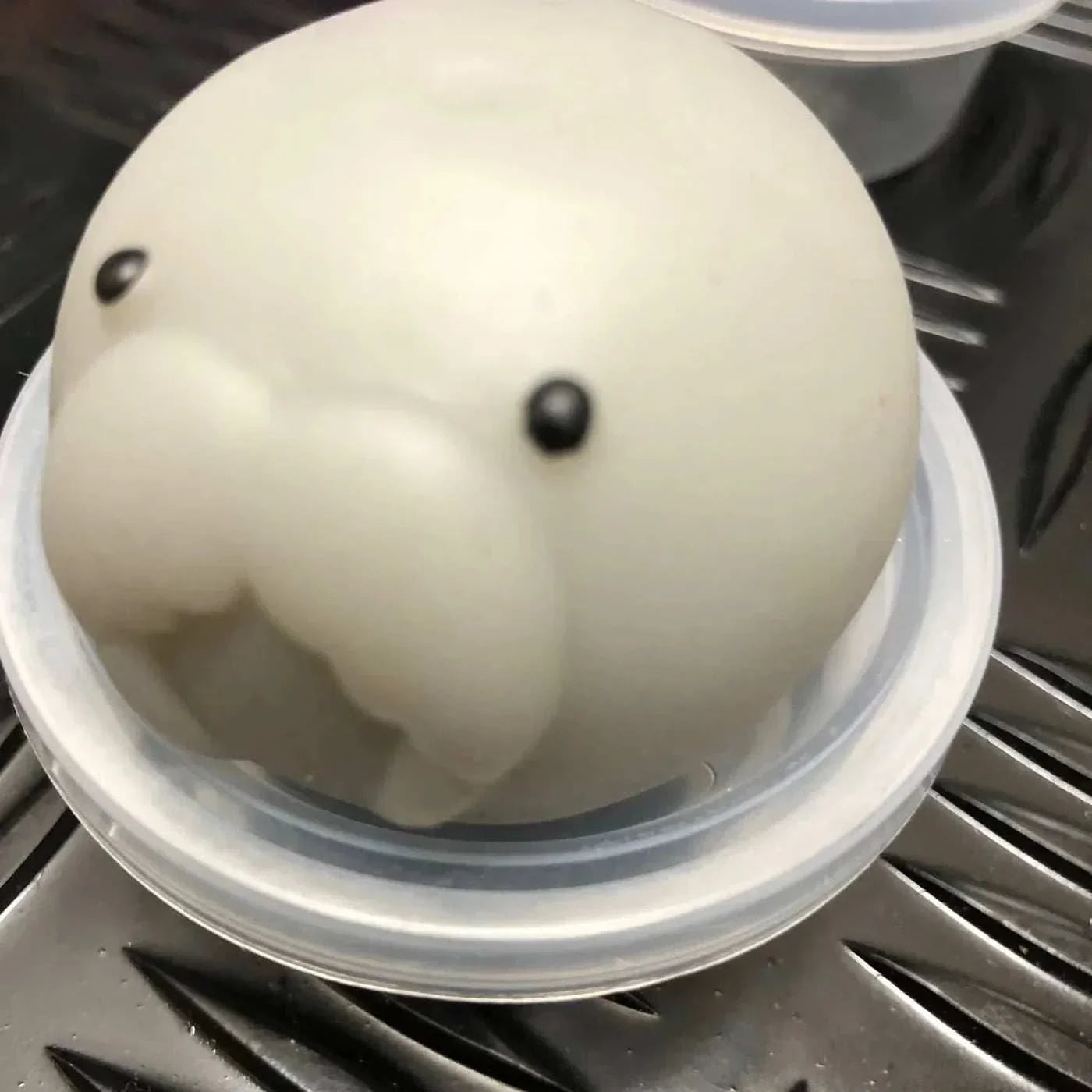 White jelly mochi squishy animal toy with black eyes in a small clear container