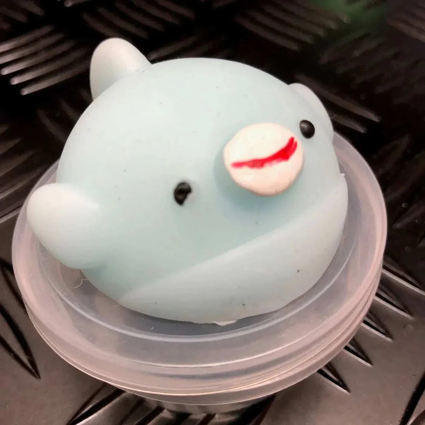 Blue Jelly Mochi Squishy Animal toy shaped like a cute bird, made from soft, non-toxic TPR material, sitting on a plastic container lid.